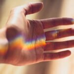 A hand with a beautiful rainbow light refraction across the palm.